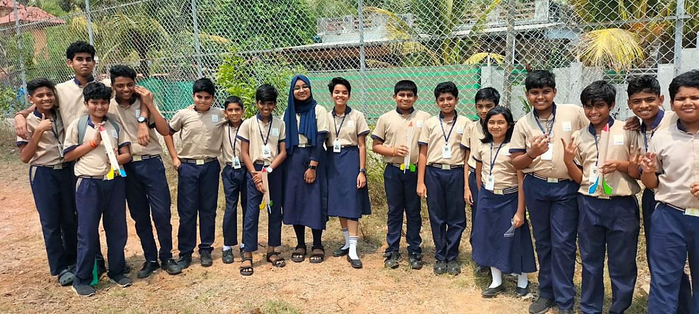 A large class of school students standing outdoors in a line, each holding the model rocket they built during an MRS session